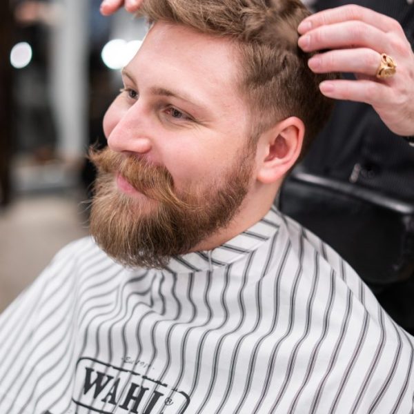 man-in-white-and-black-striped-veil-having-a-haircut-3998404